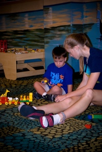 A volunteer helps a child put his train together at Friday Fun Night (photo by Ben Yoder)